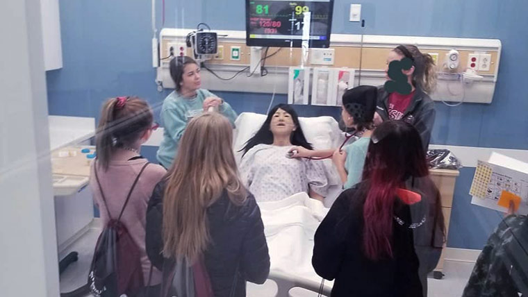 Middle school students looking over simulation patient at Expanding Your Horizons event.