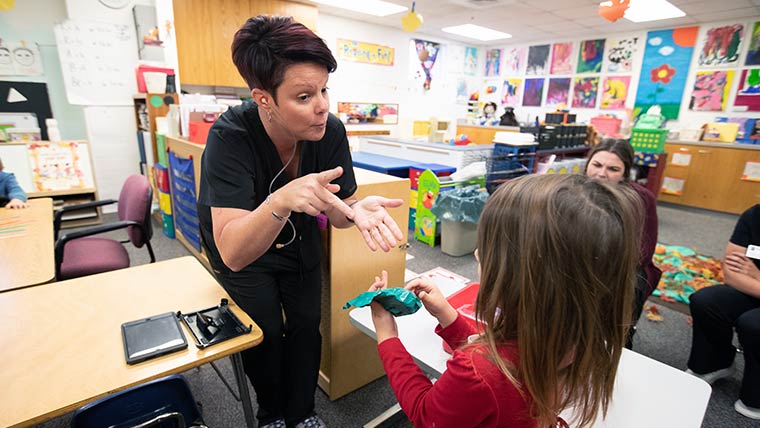 A teacher working with a hearing impaired student. 