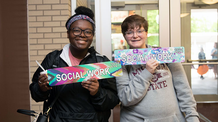 Two Missouri State social work students holding signs that say social work. 