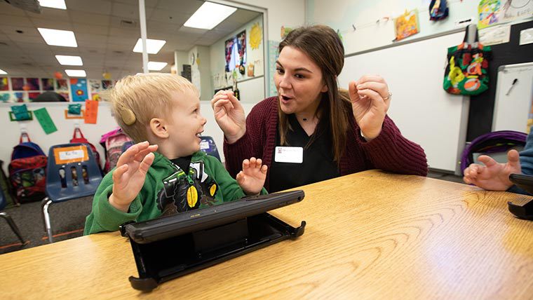 Audiology student helping hearing-impaired preschooler.
