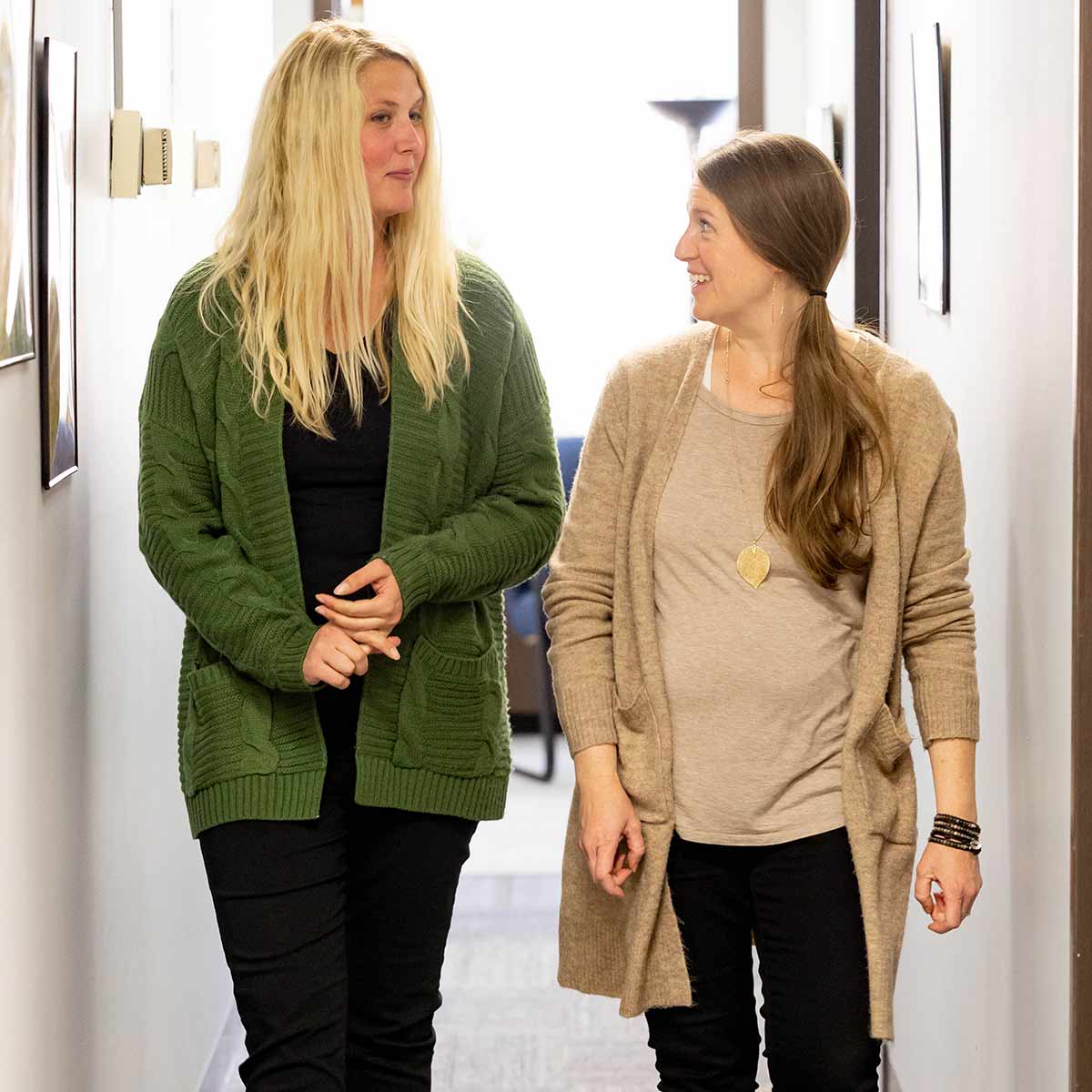 A counselor talks with a patient as they walk down a hallway together.