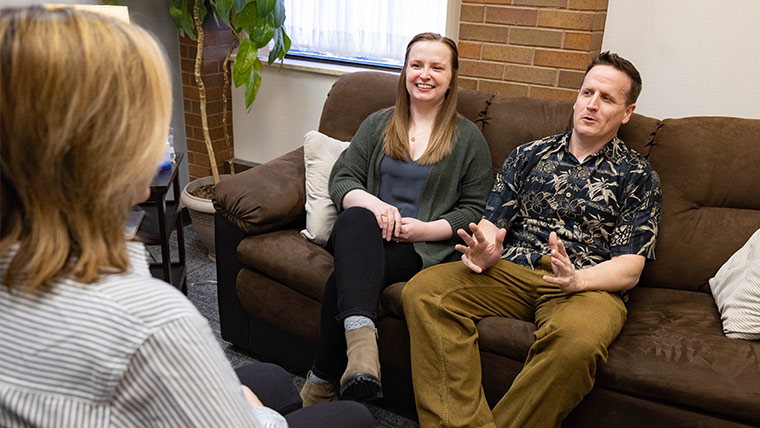 A happy couple talks with a counselor during a therapy session.