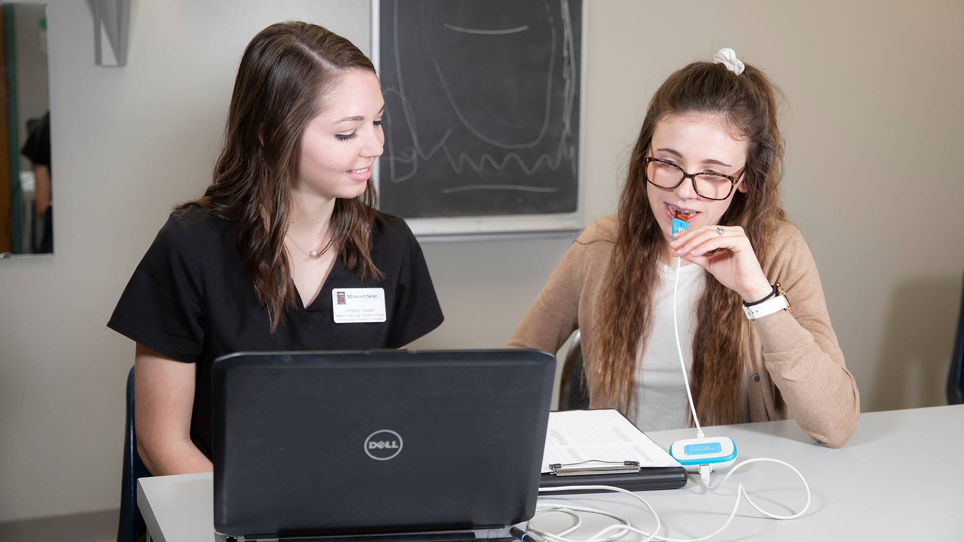 Two speech-language pathology (SLP) students using a smart palate device to test for lisping.