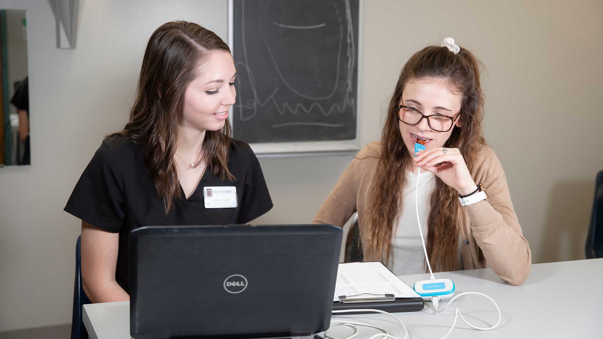 Two speech-language pathology (SLP) students using a smart palate device to test for lisping.