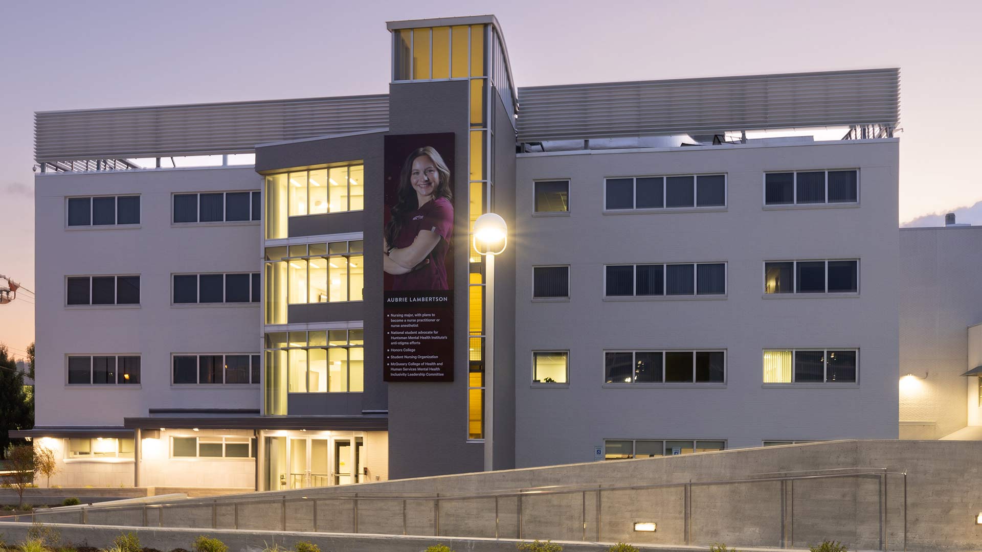 Ann Kampeter Health Sciences Hall with lights on in the early evening.