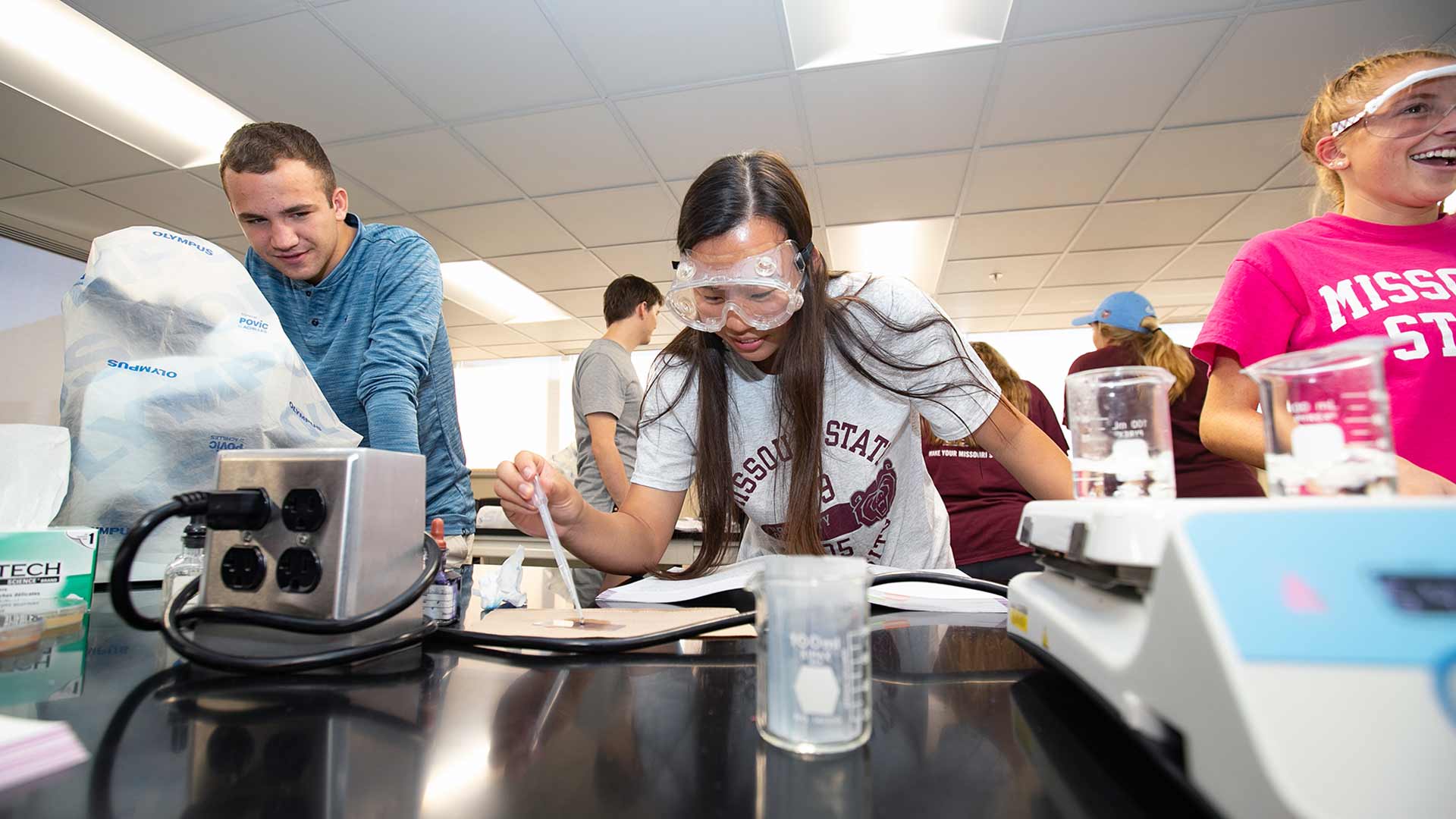 Three Missouri State students working within a biomedical lab.