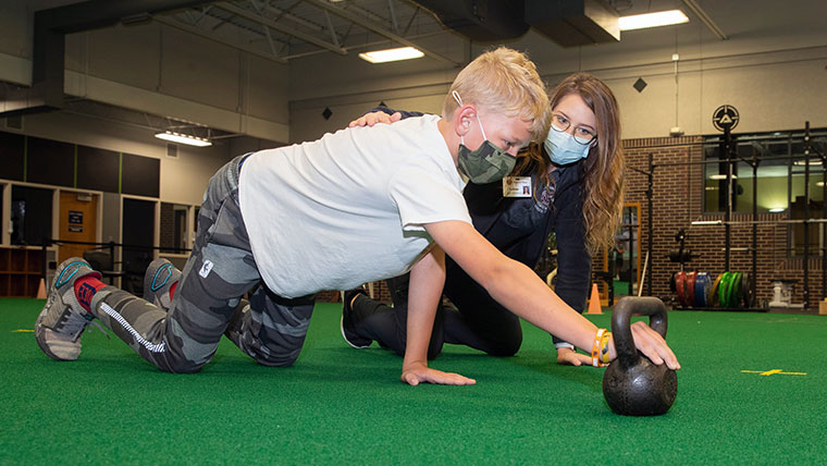 A Missouri State student helping a future Bear exercise with a kettlebell. 